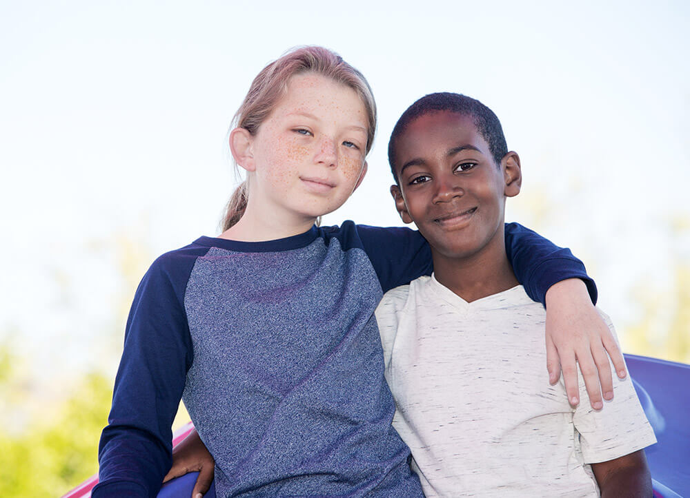 child with adopted brother embracing outside